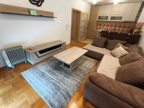Dnevna soba sa garniturom, stočićem i pogledom na kuhinju u pozadini. - image 16