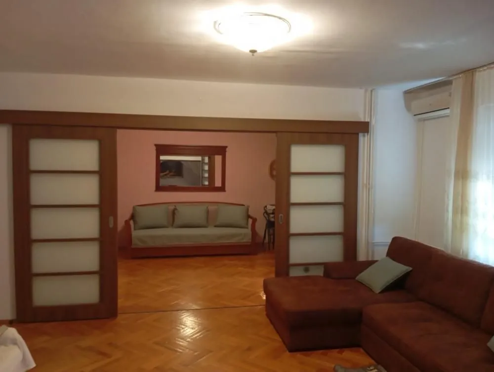 Spacious living room with a sofa and sliding wooden doors leading to another room.