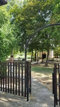 Pogled kroz drvenu kapiju na dvorište i zelenilo ispred kuće. - image 10