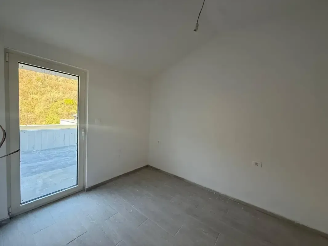 Prazna neuređena prostorija sa balkonskim vratima i izlazom na terasu.