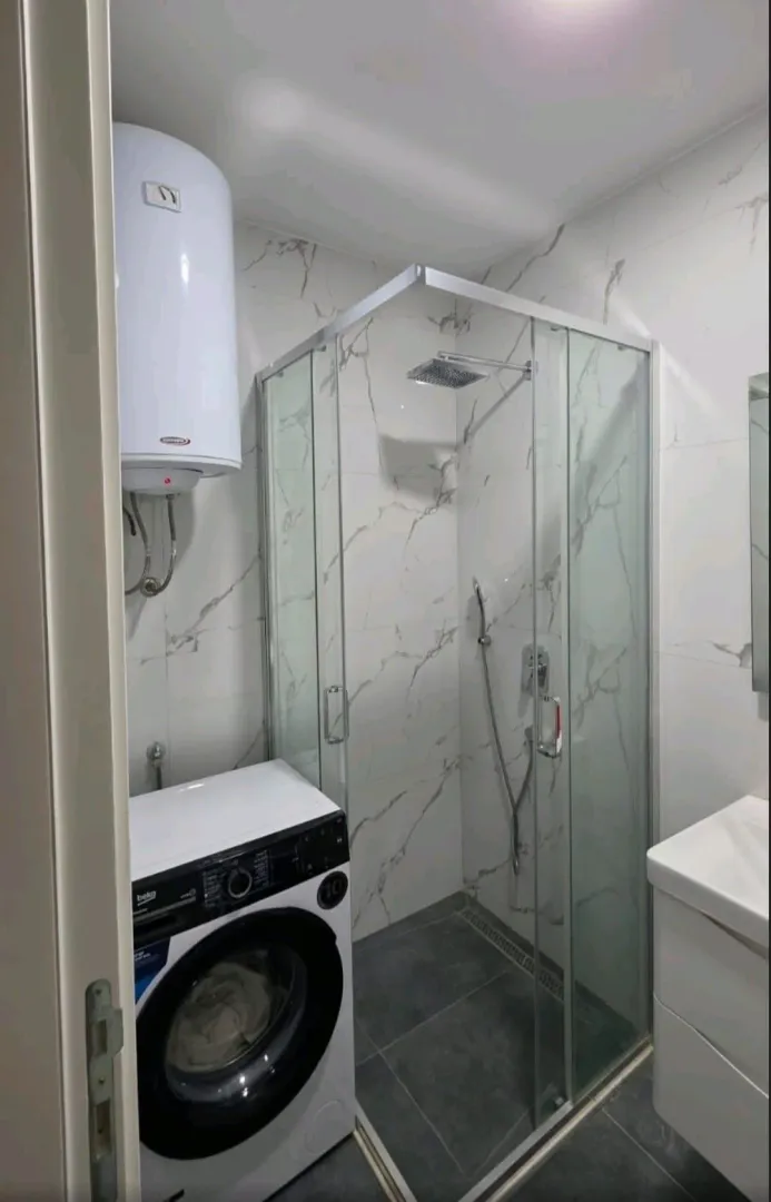Moderno opremljeno kupatilo sa tuš kabinom, bojlerom i veš mašinom.