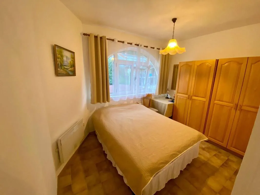 Namještena spavaća soba sa bračnim krevetom, ormarom i prozorom.