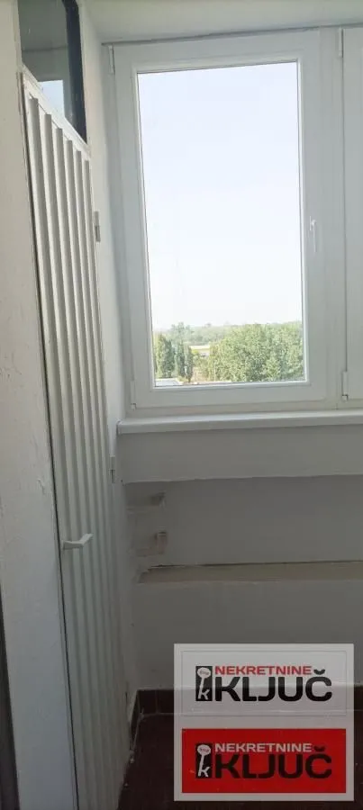 Zastakljeni balkon sa pogledom na zelenilo i okruženje.