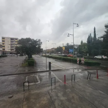 View of the street and parking lot in front of the building on a cloudy day. - image 11
