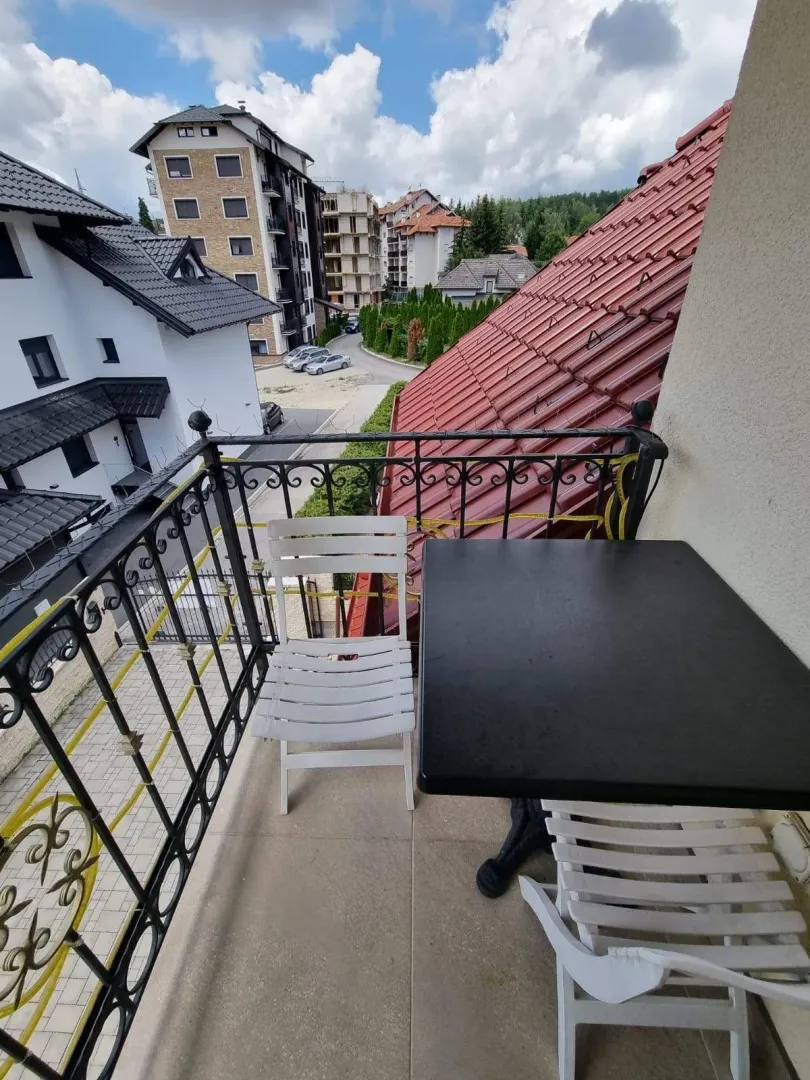 Manji balkon sa stolom i stolicama i pogledom na naselje.