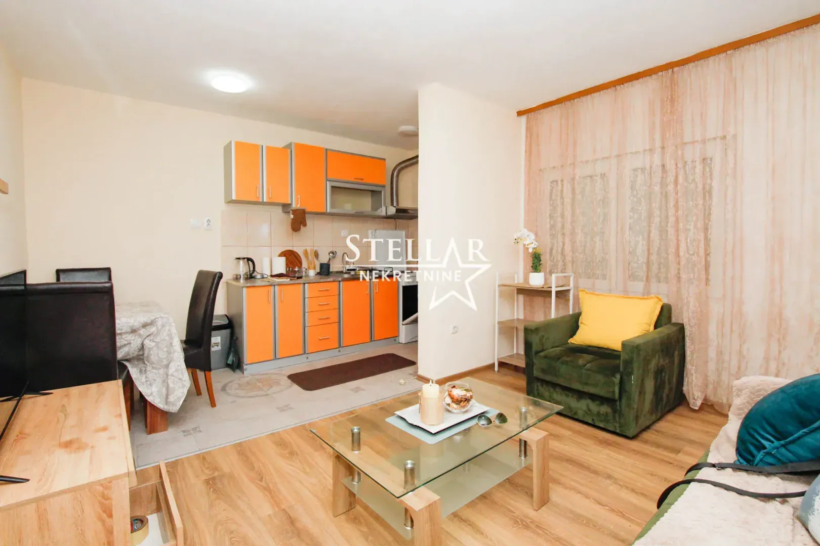 Living room with dining area and connected kitchen in orange tones.