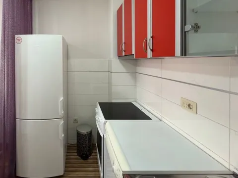 Manja kuhinja sa crvenim visećim elementima i bijelim frižiderom. - image 5