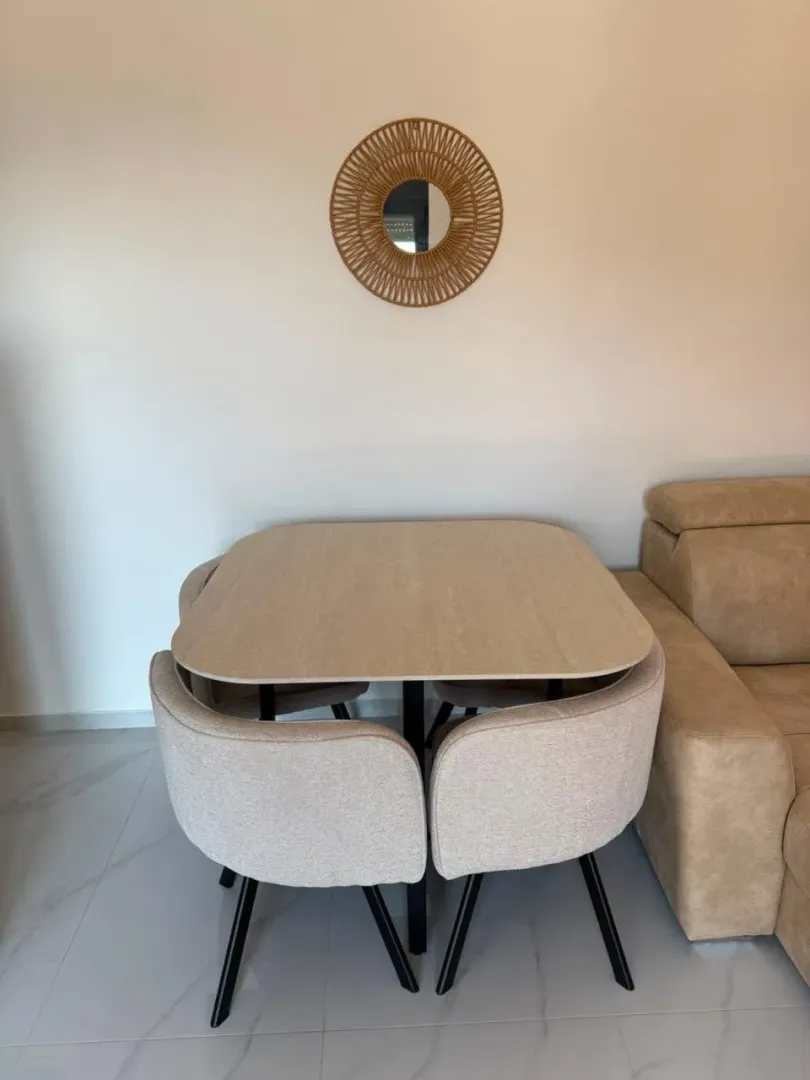 Dining table with four chairs and a decorative wall mirror in the living room.