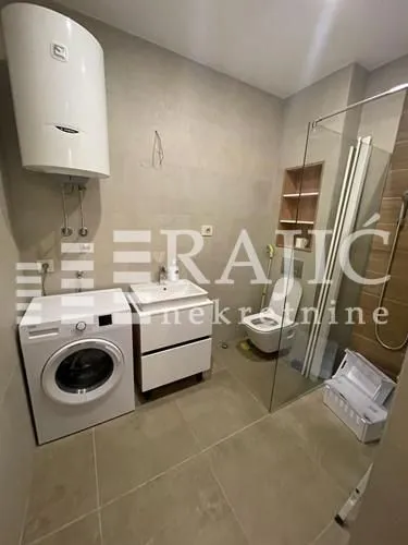 Modernly equipped bathroom with a shower cabin, sink, and washing machine.