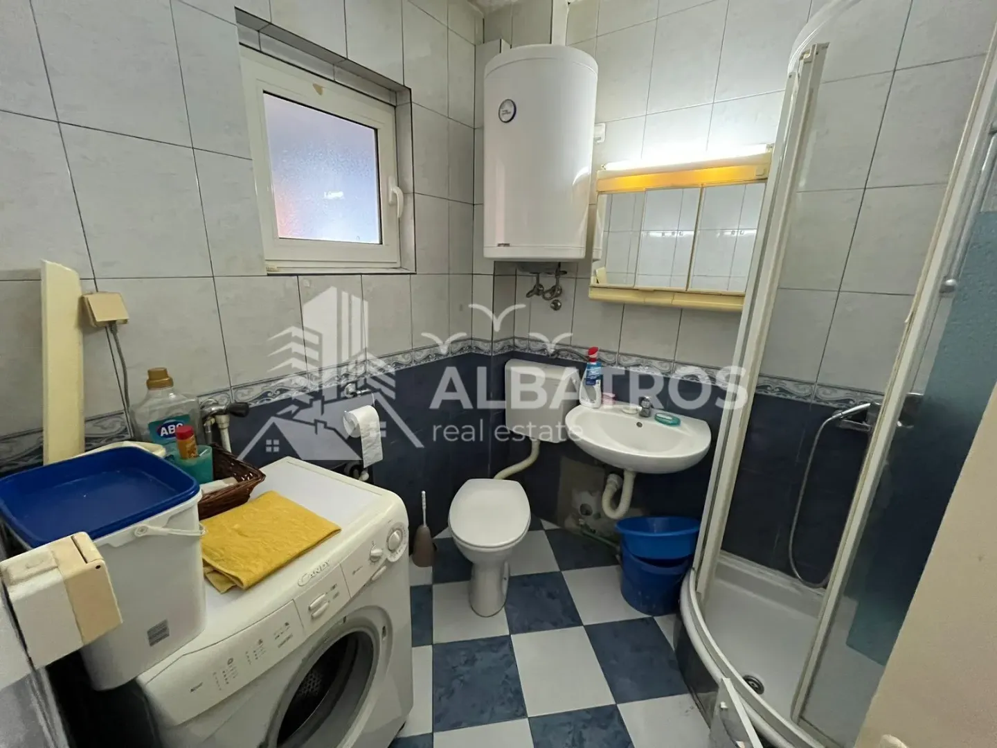 Kupatilo opremljeno tuš kabinom, umivaonikom, wc šoljom i mašinom za veš.
