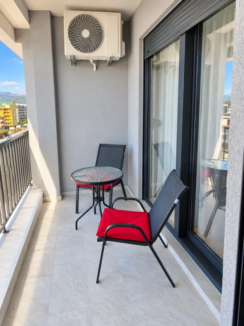 Manji natkriveni balkon sa garniturom za sedenje i pogledom na okolinu.