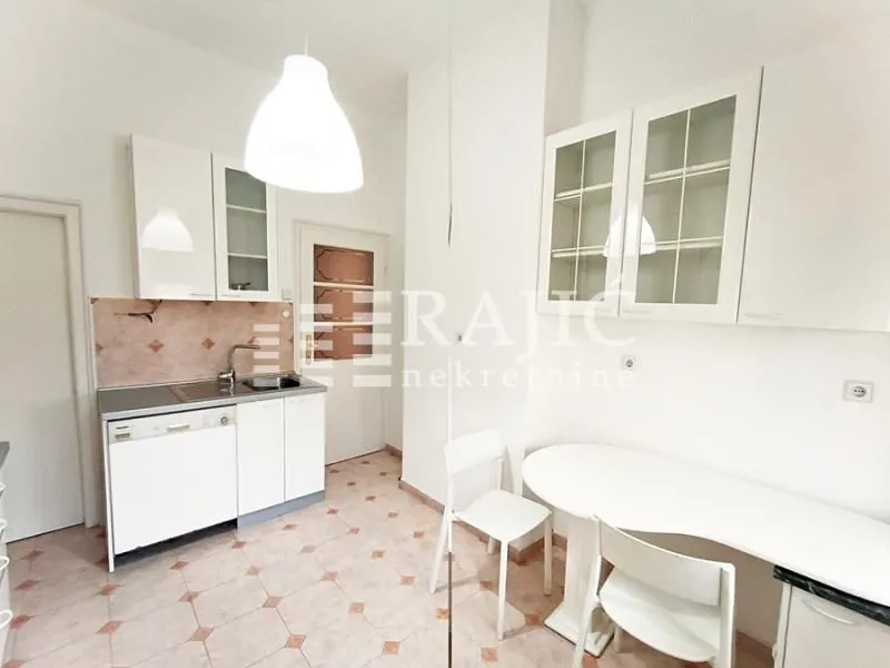 Small white kitchen with a dining table and chairs.