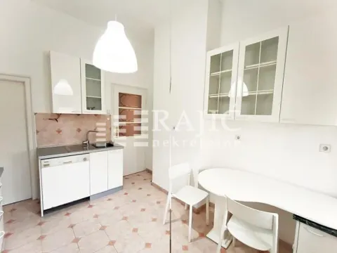 Small white kitchen with a dining table and chairs. - image 3