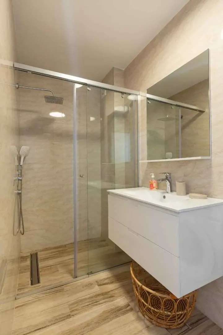 Modern bathroom with a walk-in shower, washbasin, and mirror.