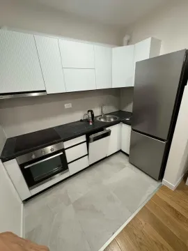 Modern kitchen with white cabinetry, dark countertops, and built-in appliances. - image 13