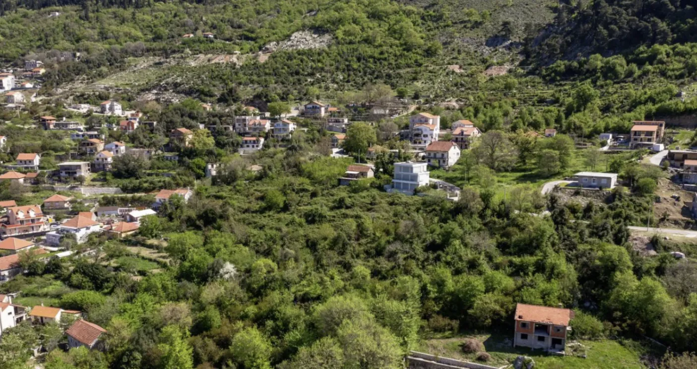 Pogled iz vazduha na naselje sa zelenilom i kućama.