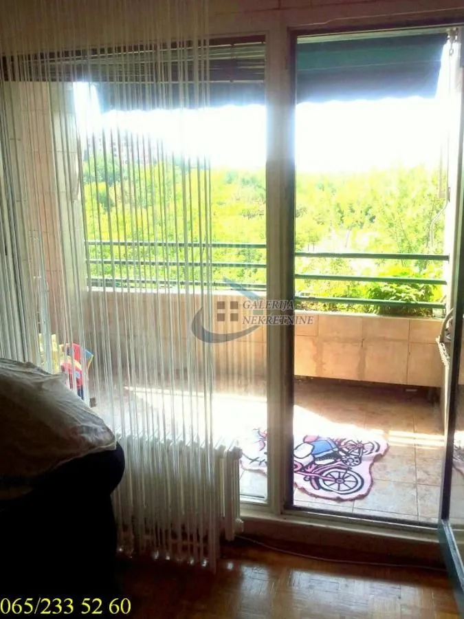 Pogled na terasu sa zelenilom kroz balkonska vrata.