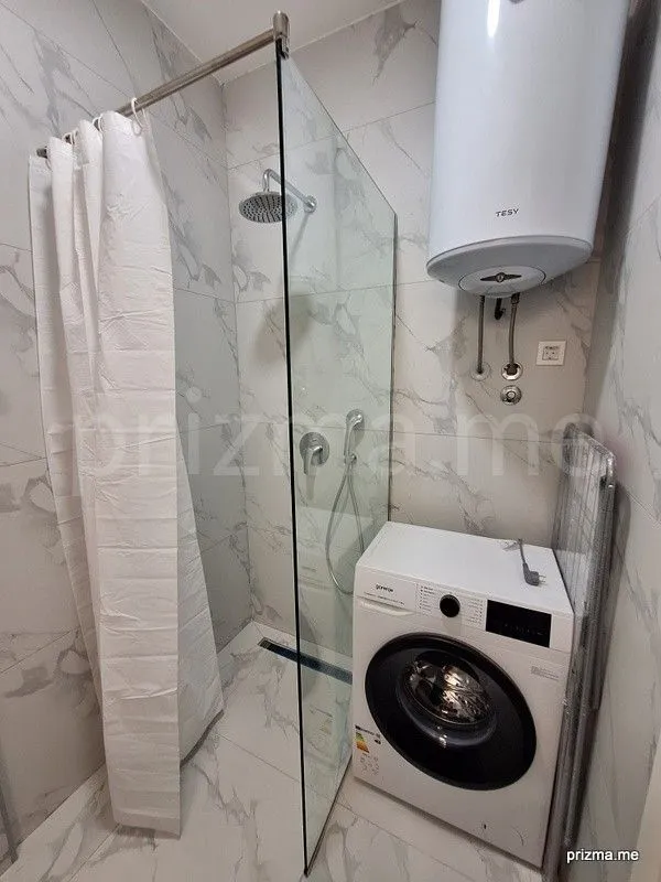 Modern bathroom with a shower cabin, water heater, and washing machine.