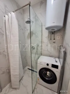 Modern bathroom with a shower cabin, water heater, and washing machine. - image 9