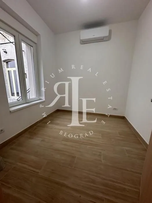 Empty room with laminate flooring, white walls, an air conditioner, and a window.