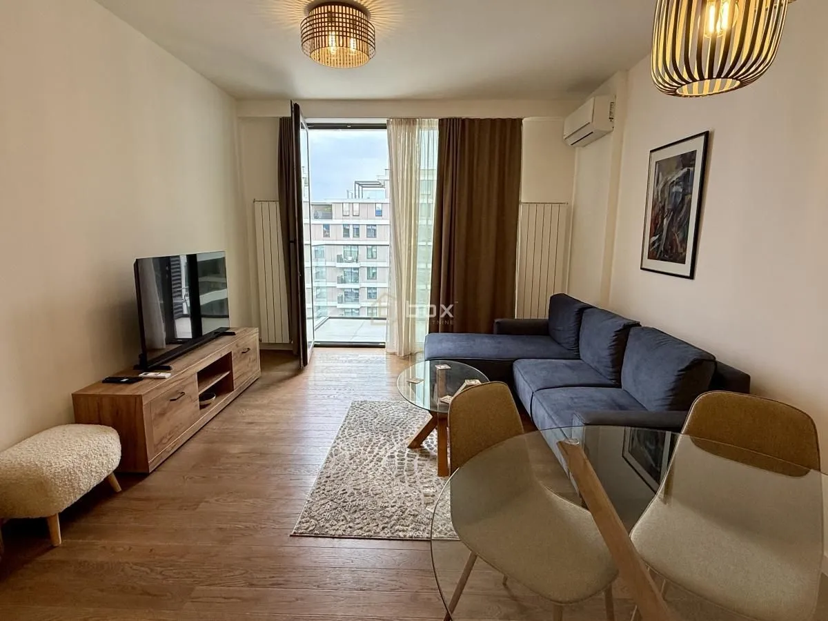 Living room with sofa, TV unit, and dining table, with access to the terrace.