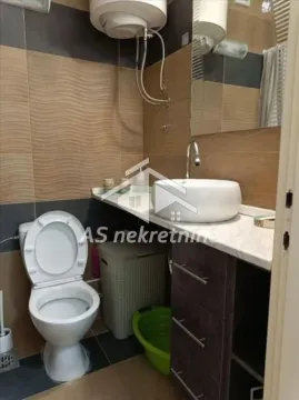 Small bathroom with a toilet, washbasin, and brown-toned tiles. - image 16