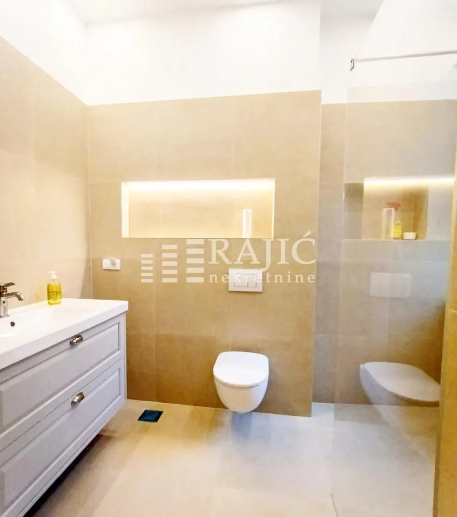Modernly equipped bathroom with a washbasin, toilet, and walk-in shower.