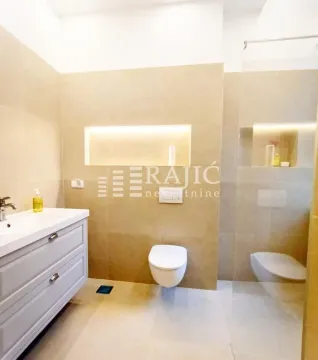 Modernly equipped bathroom with a washbasin, toilet, and walk-in shower. - image 15