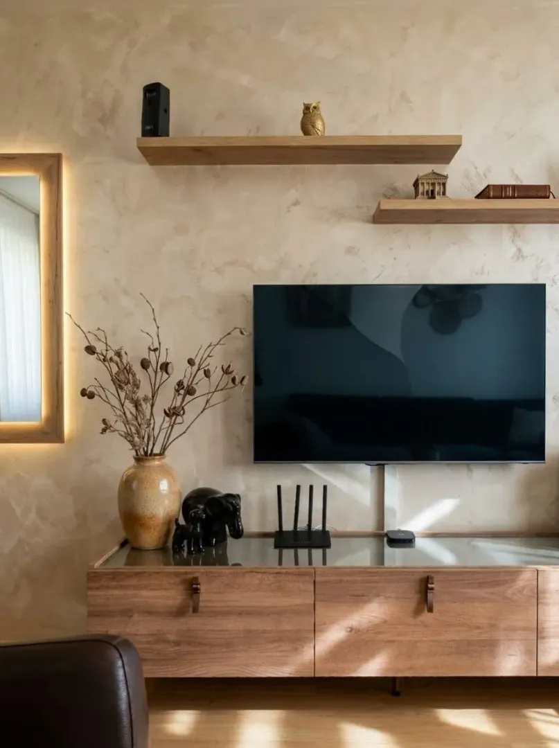 Living room with a TV, wooden console unit, and wall shelves.