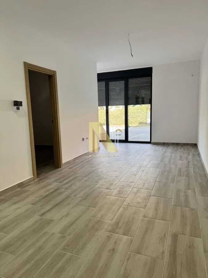 Prazna soba sa svetlim laminatom i vratima prema terasi.