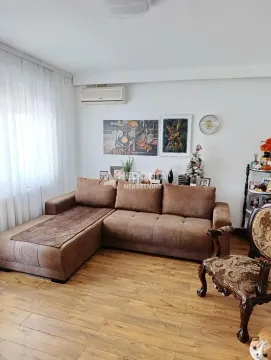 Dnevna soba sa ugaonom garniturom, drvenim podom i slikama na zidu. - image 2
