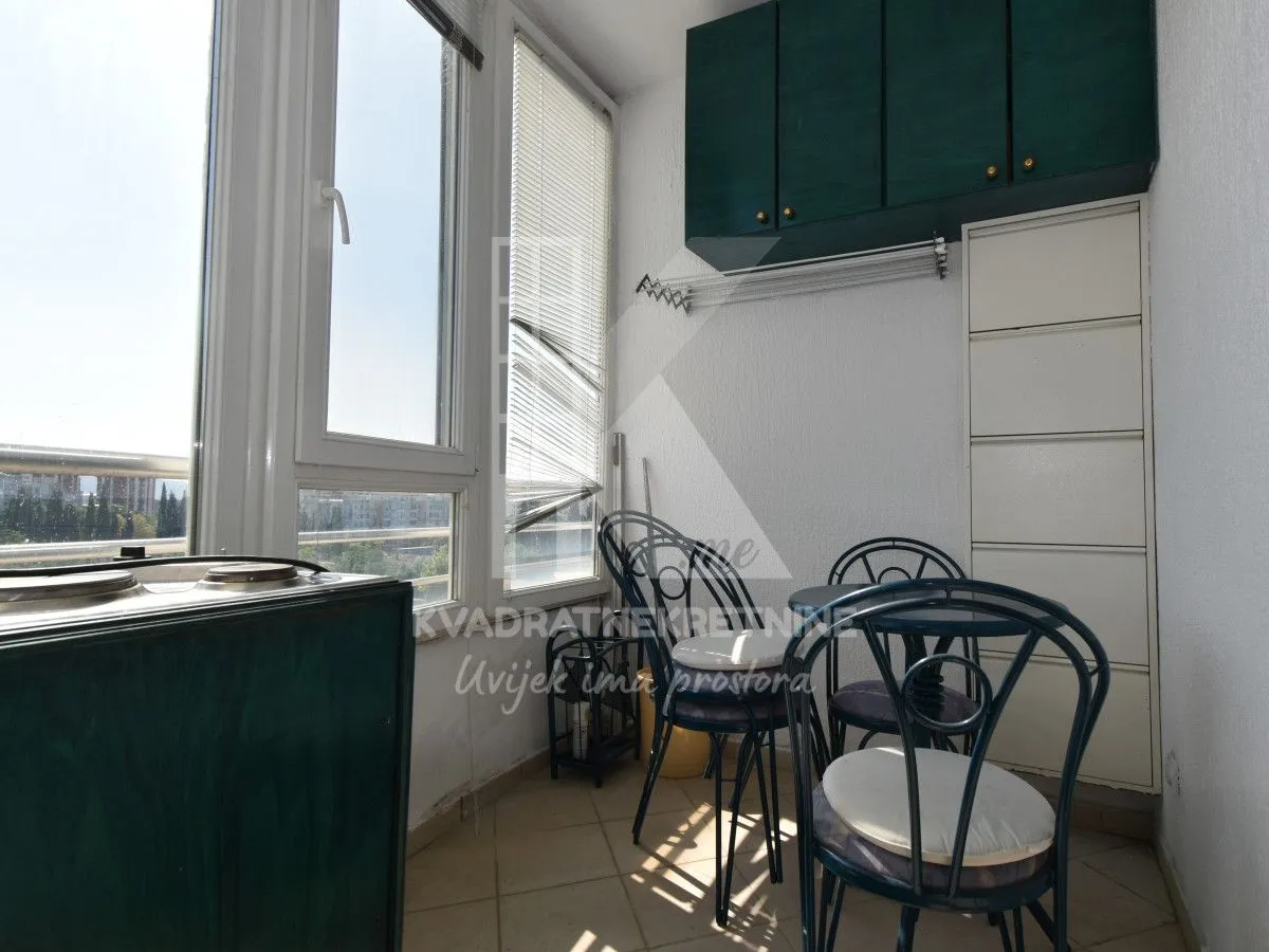 Enclosed balcony with seating furniture and storage units.