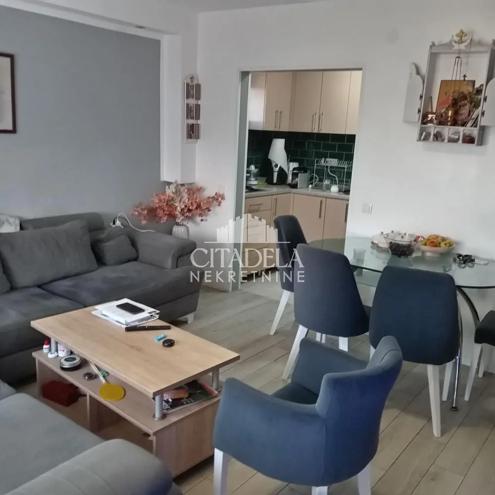 Dnevna soba sa garniturom, stočićem i trpezarijom u nastavku.