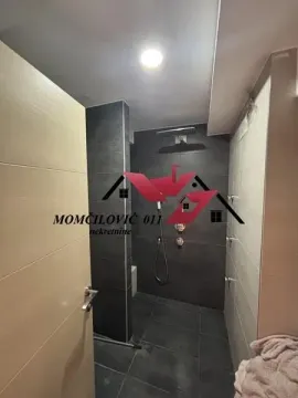 Pogled na moderno uređeno kupatilo sa tuš kabinom obloženom tamnim pločicama. - image 3