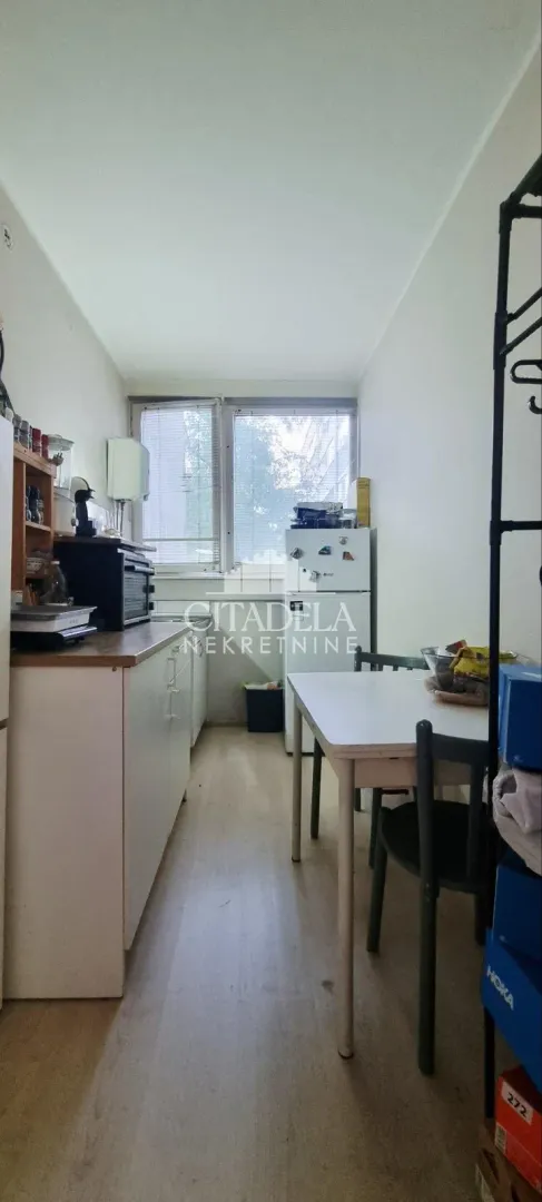 Manja kuhinja sa trpezarijskim stolom i prozorom na kraju prostorije.