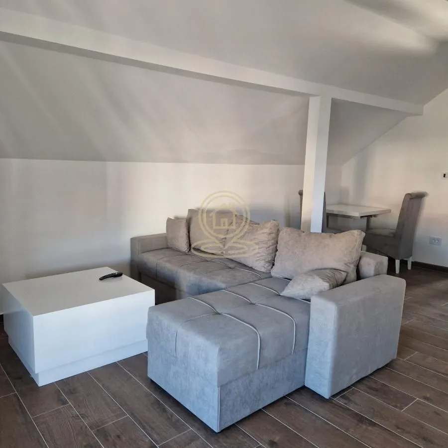 Living room with a sectional sofa and coffee table under a sloped ceiling.