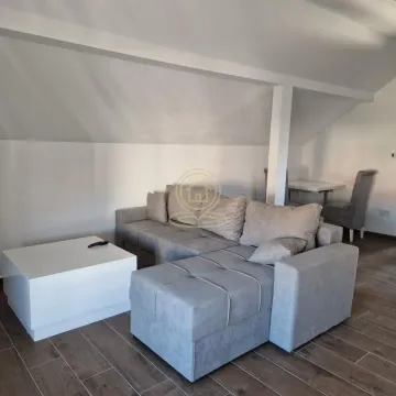 Living room with a sectional sofa and coffee table under a sloped ceiling. - image 2