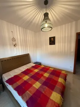 Spavaća soba sa bračnim krevetom, šarenim prekrivačem i lusterom na plafonu. - image 8