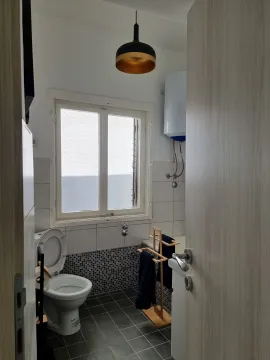 Small bathroom with a window, toilet, and water heater. - image 11