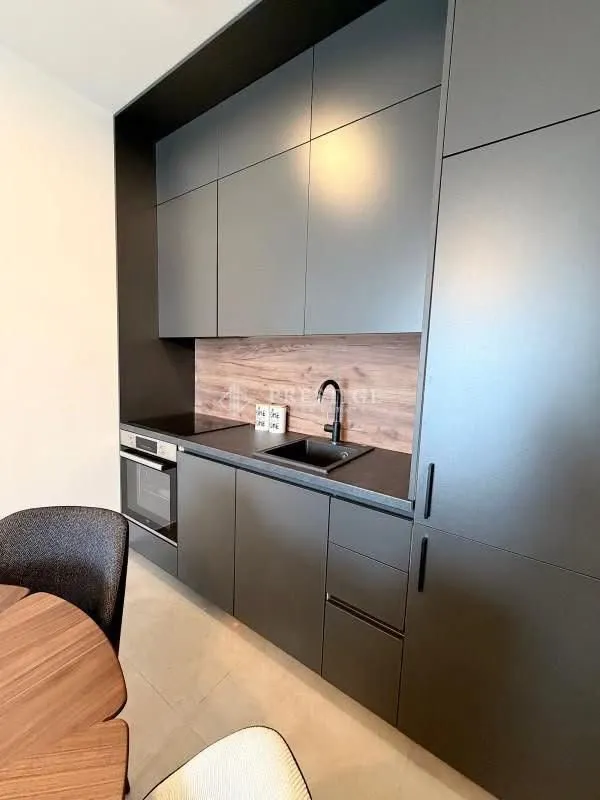 Modern kitchen with dark cabinets and a dining table.