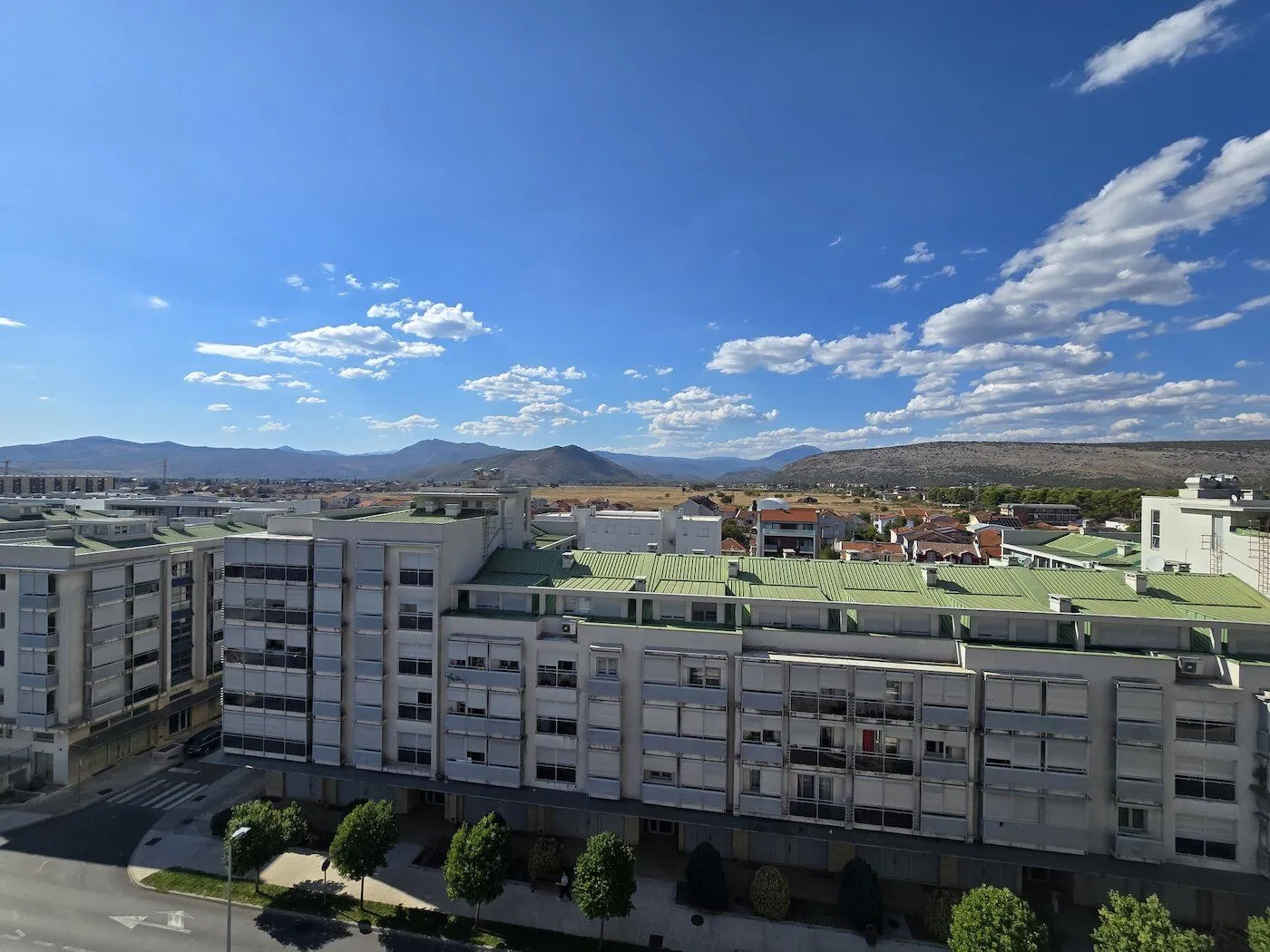 View from the terrace overlooking residential buildings and surrounding mountains.