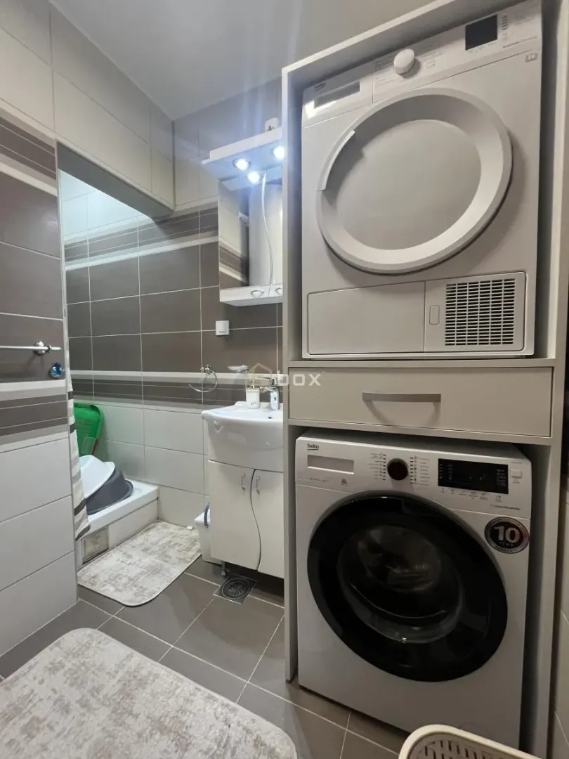 Bathroom equipped with a sink, shower cabin, and laundry machines.