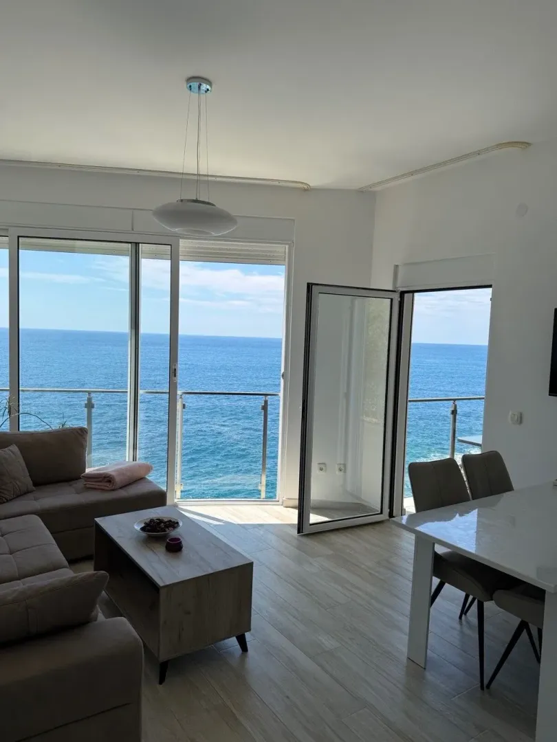 Living room with dining area and a sea view through large glass balcony doors.