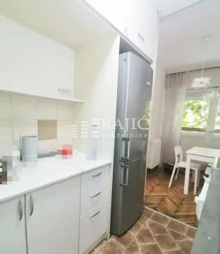Small white kitchen with a refrigerator and a view of the dining area. - image 2