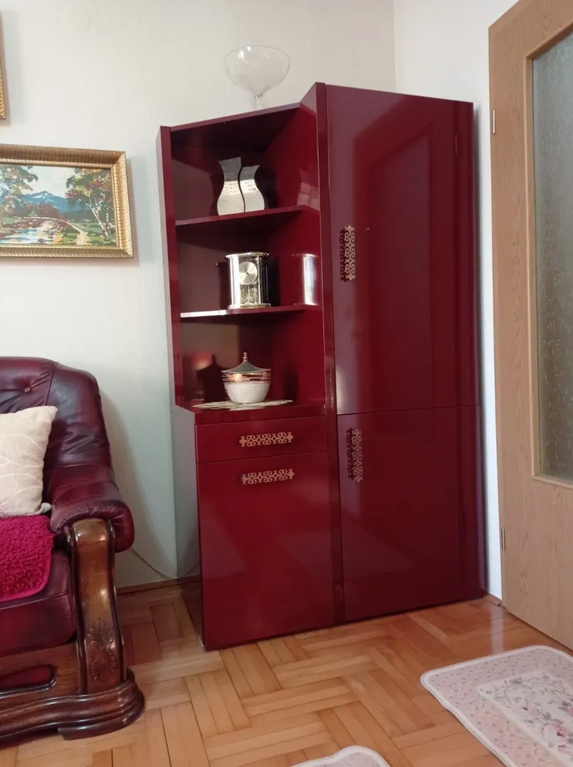 Part of a living room featuring a red cabinet and a leather armchair next to a door.