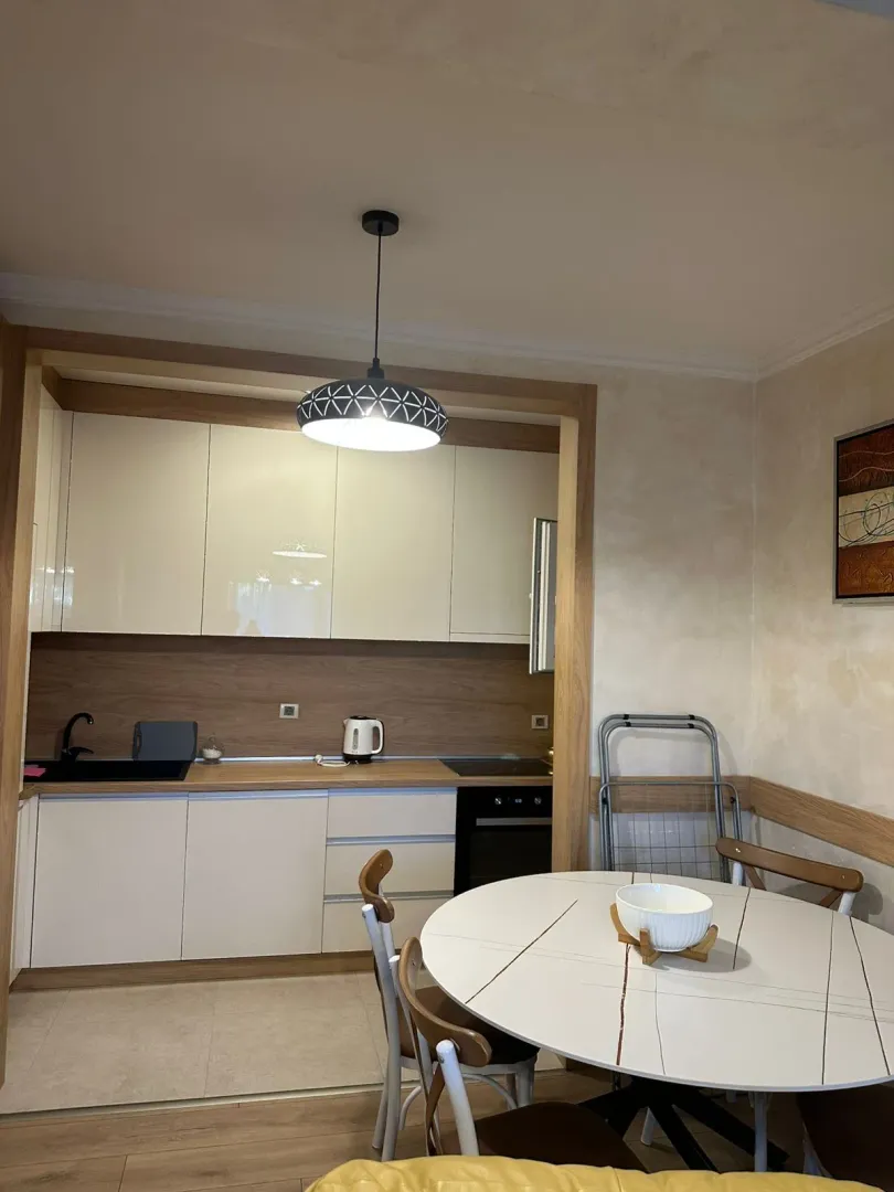 Dining area with a round table and a view of the kitchen in the background.