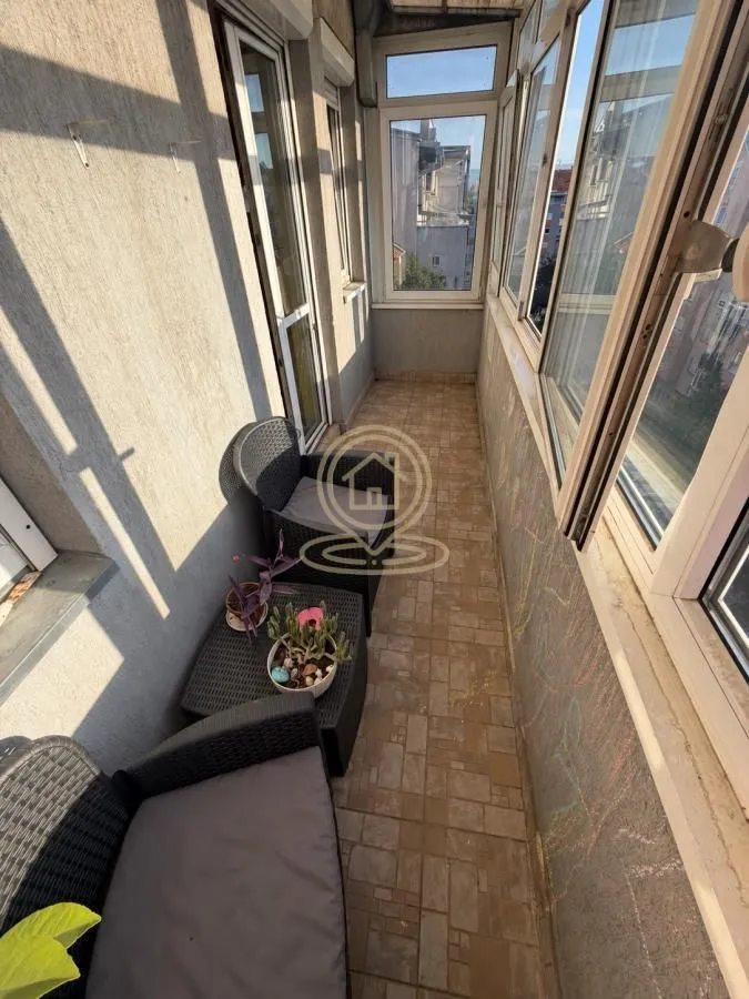 Zastakljeni balkon sa garniturom za sedenje.