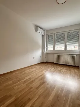 Prazna soba sa parketom, klima uređajem i prozorom sa roletnama. - image 12