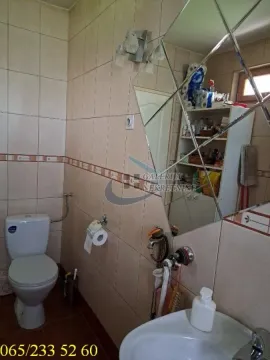 Manje kupatilo obloženo keramičkim pločicama sa toaletom, umivaonikom i velikim ogledalom. - image 9