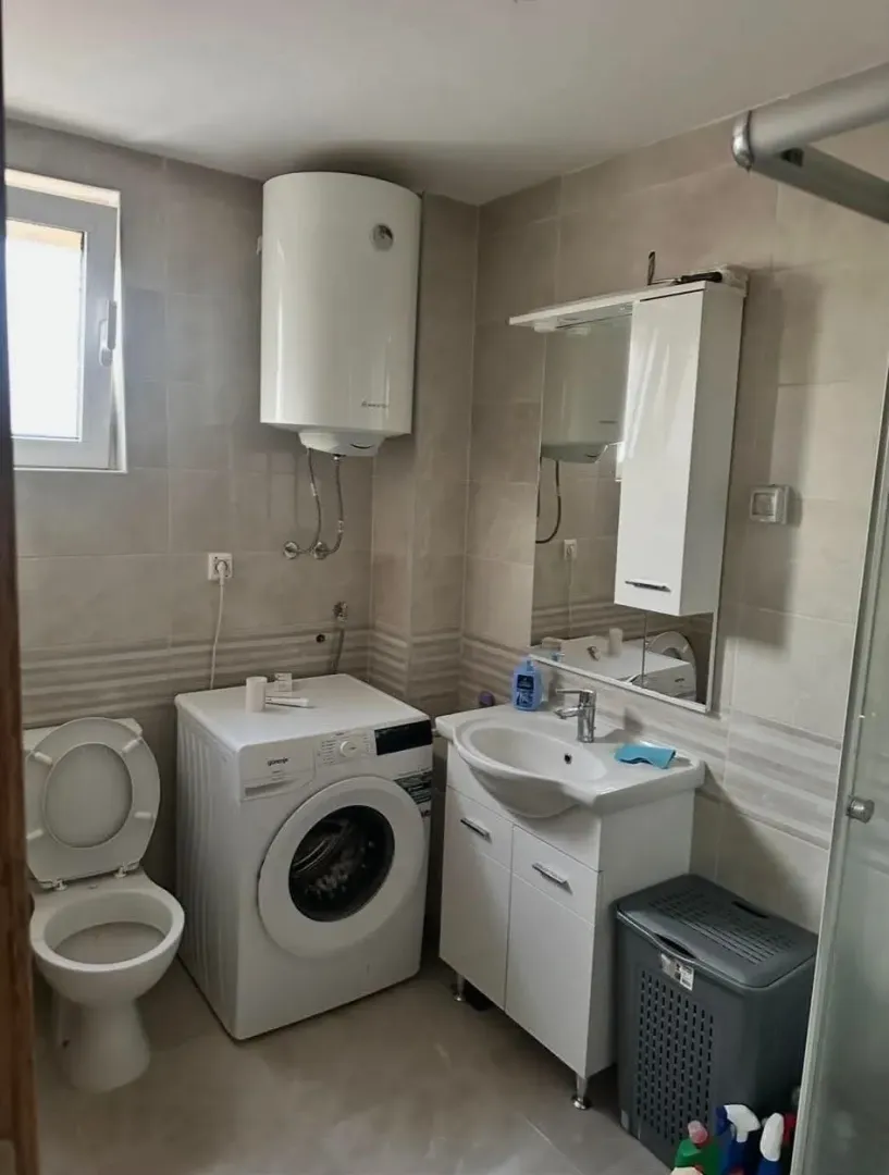 Smaller bathroom with a shower cabin, sink, and washing machine.